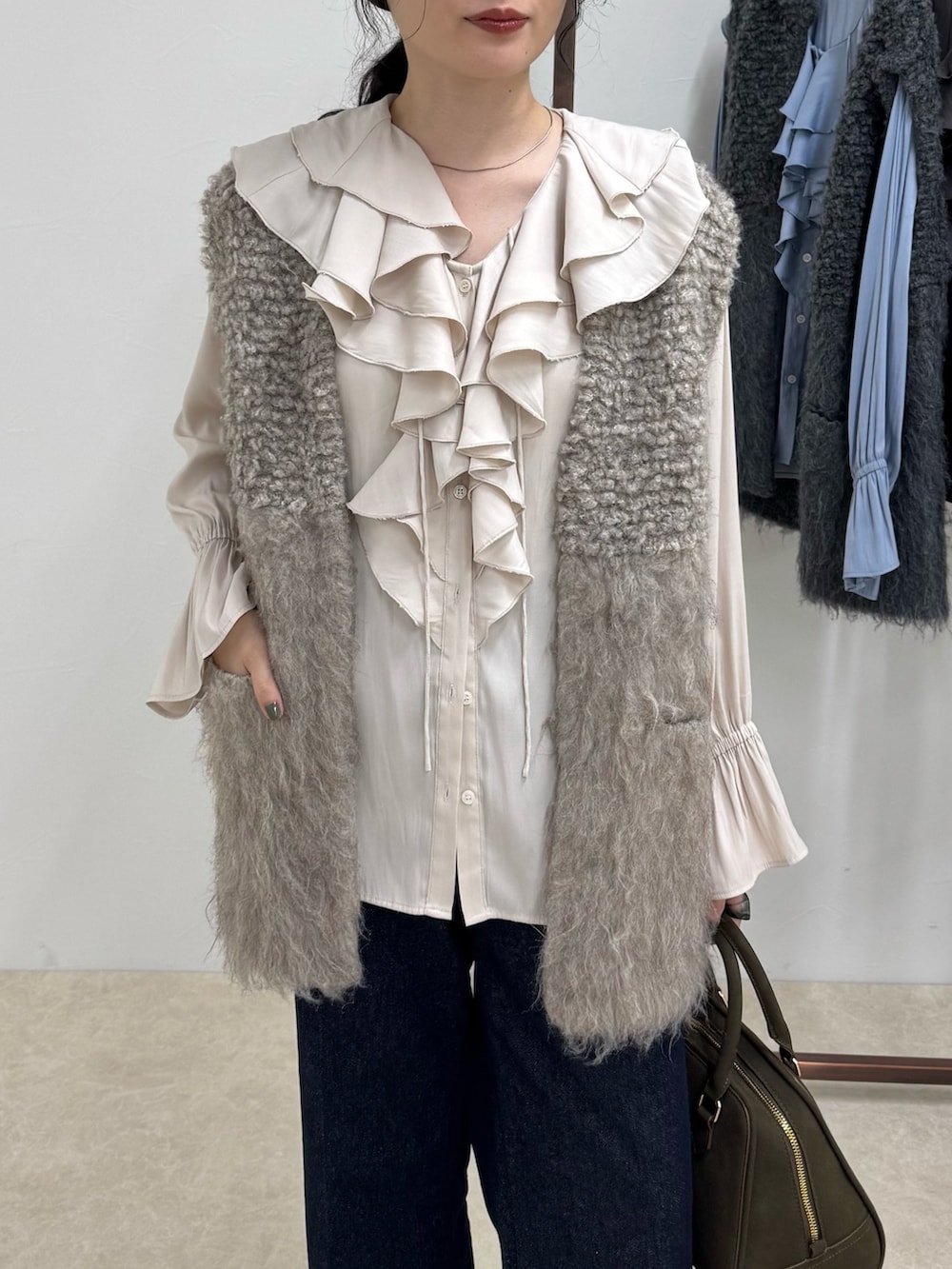 ホワイト系のシャツ/ブラウス、ベージュ系のベスト、ブルー系のデニムパンツを着用したレディースの秋コーディネートの4枚目の写真