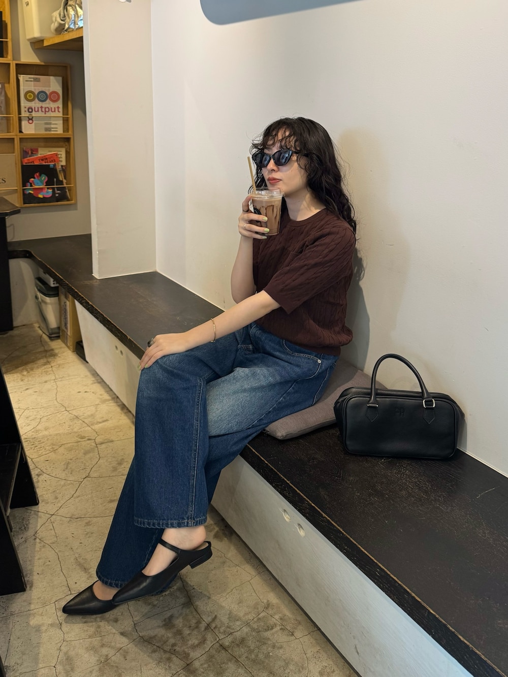ブラウン系のニット/セーター、ブルー系のデニムパンツ、ブラック系のショルダーバッグを着用したレディースの夏コーディネートの6枚目の写真