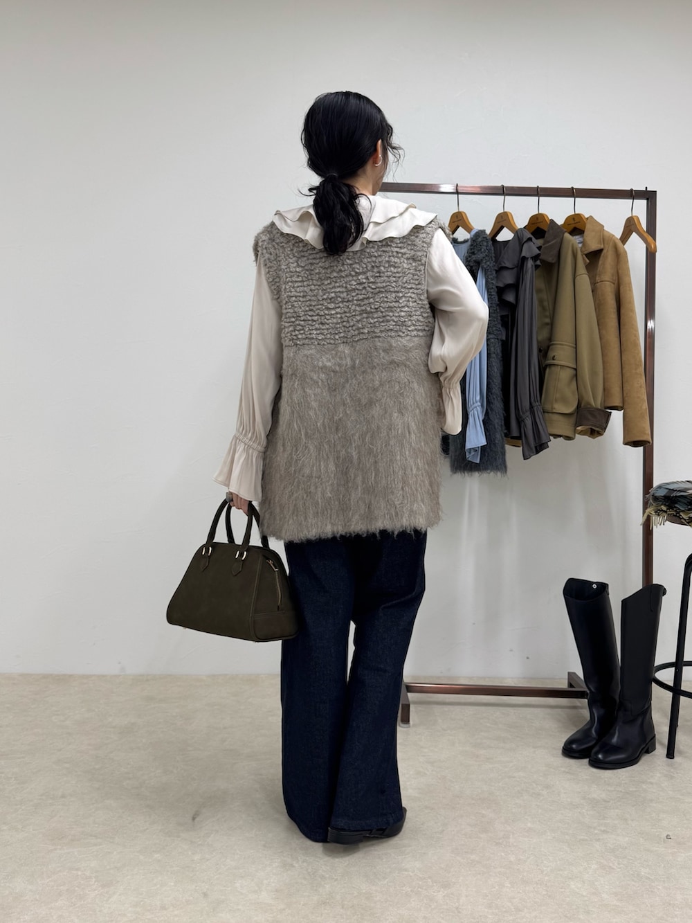 ホワイト系のシャツ/ブラウス、ベージュ系のベスト、ブルー系のデニムパンツを着用したレディースの秋コーディネートの3枚目の写真