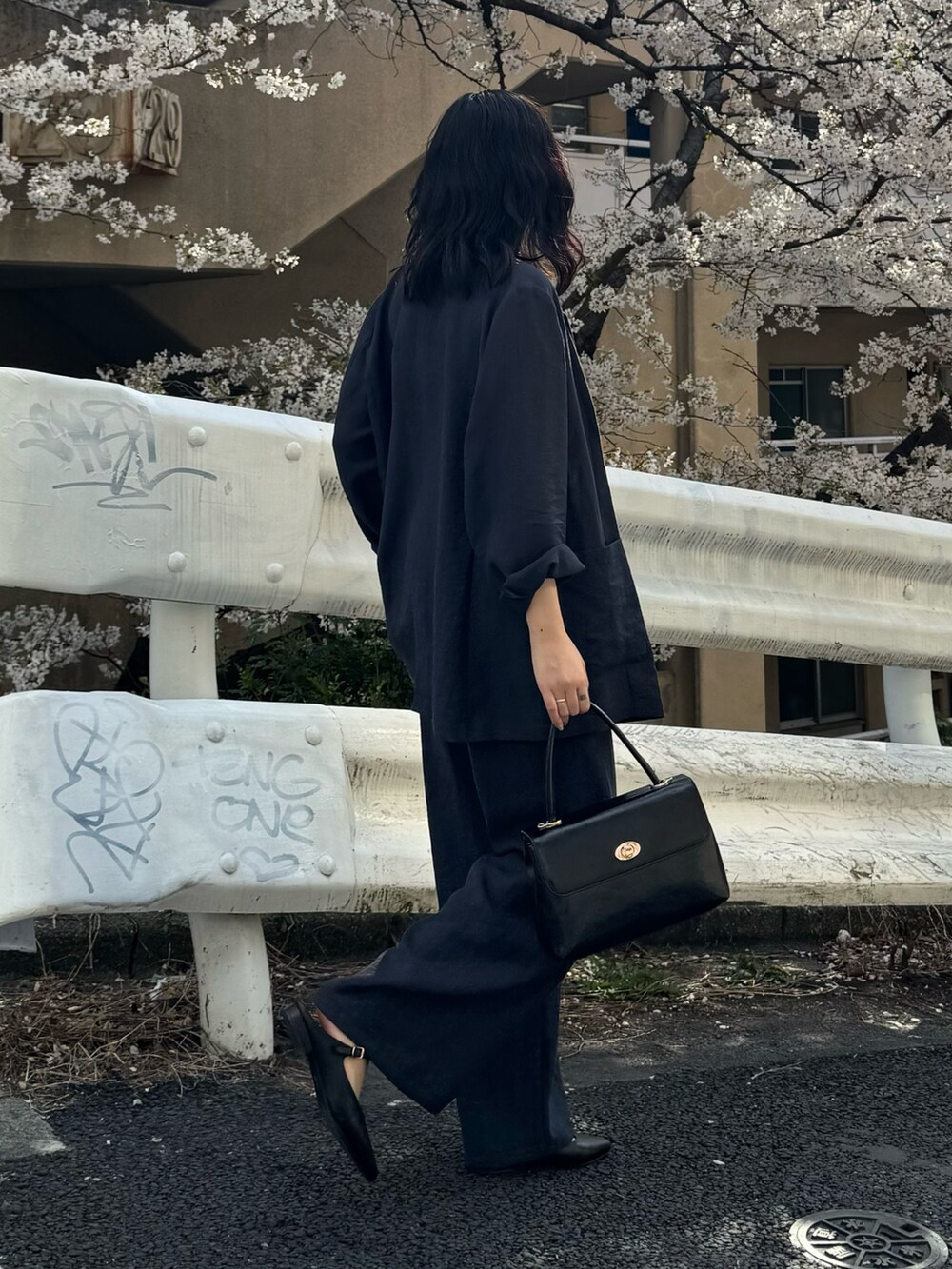 ブルー系のテーラードジャケット、ブルー系のその他パンツ、ブラック系のショルダーバッグを着用したレディースの春コーディネートの2枚目の写真
