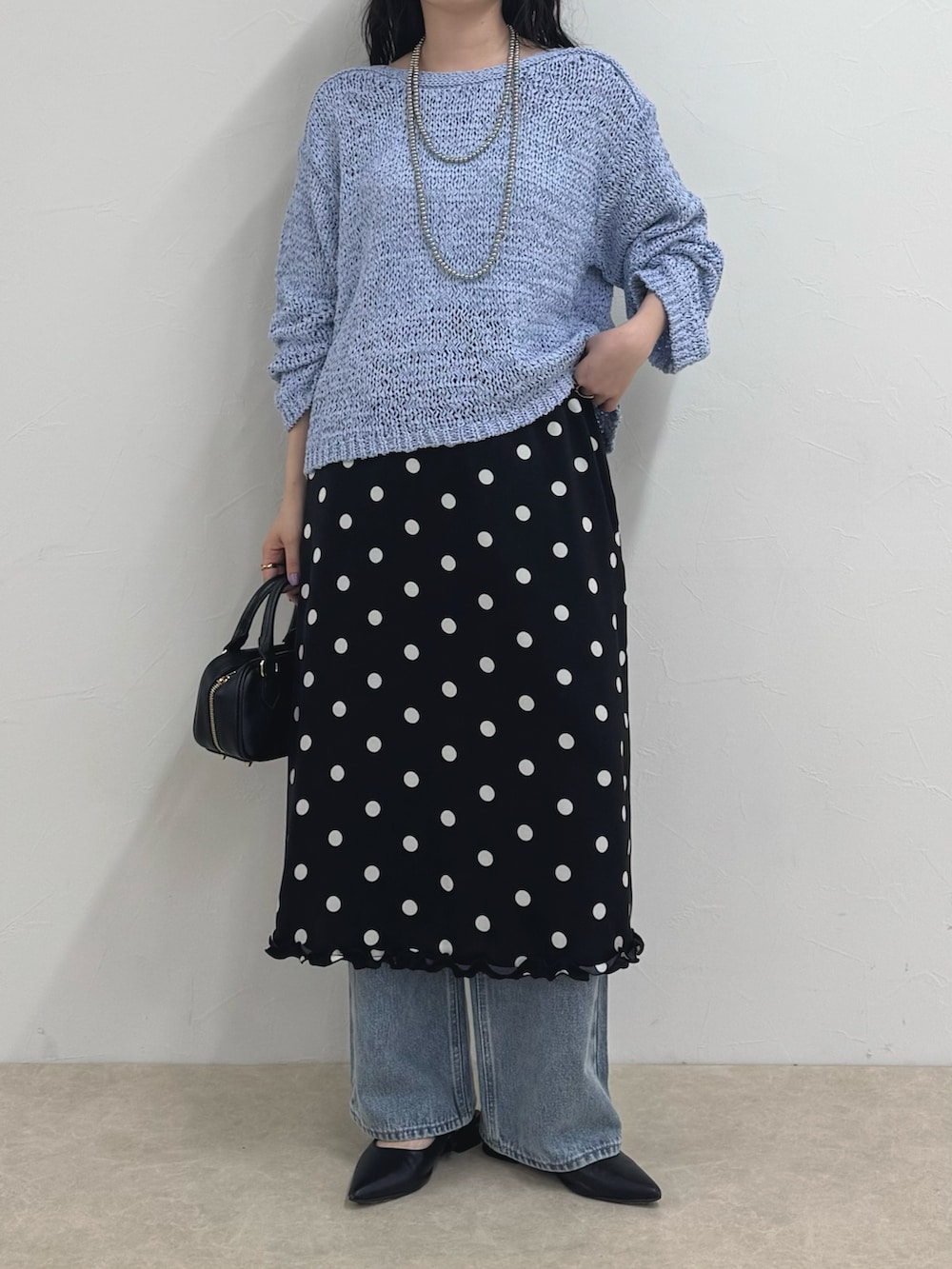 ブルー系のニット/セーター、ブラック系のスカート、ブルー系のデニムパンツを着用したレディースの春コーディネートの6枚目の写真