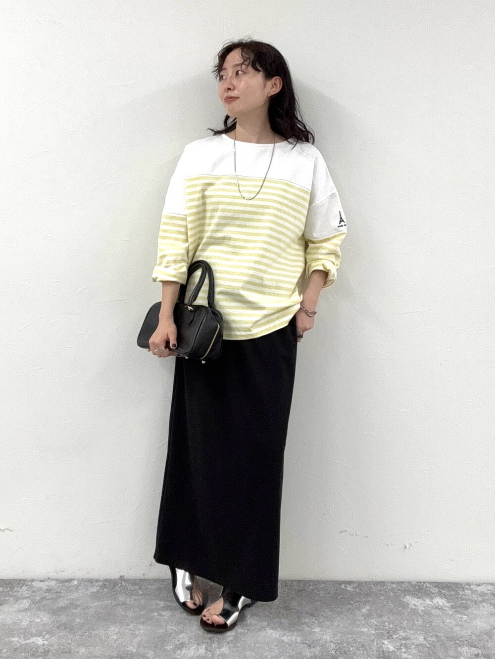 イエロー系のTシャツ/カットソー、ブラック系のスカート、ブラック系のショルダーバッグを着用したレディースの春コーディネートの7枚目の写真