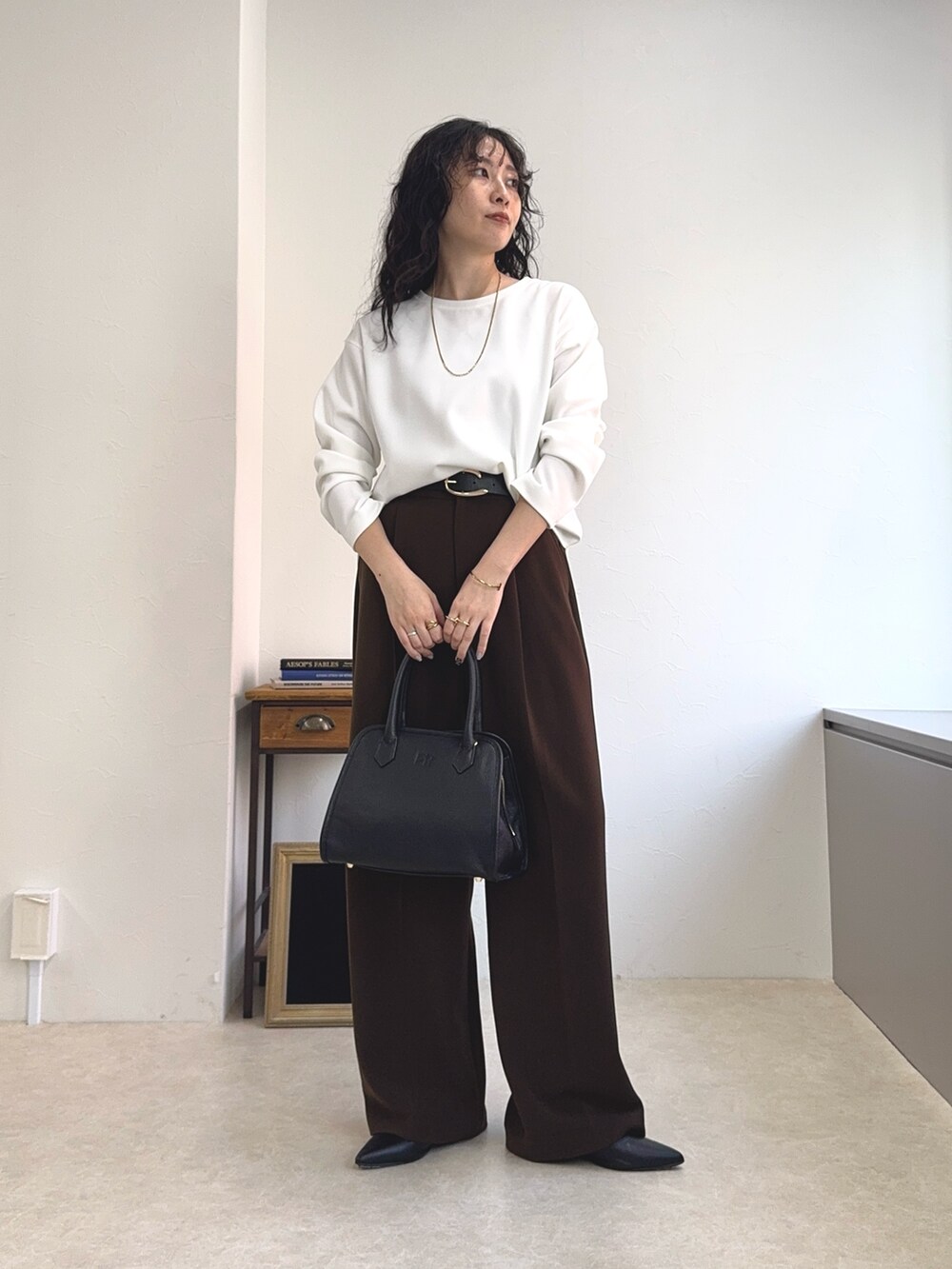 ホワイト系のTシャツ/カットソー、ブラック系のショルダーバッグ、ブラウン系のスラックスを着用したレディースの夏コーディネートの2枚目の写真