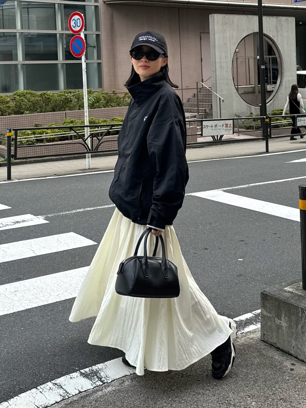 ホワイト系のスカート、グレー系のスウェット、ブラック系のマウンテンパーカーを着用したレディースの秋コーディネートの3枚目の写真