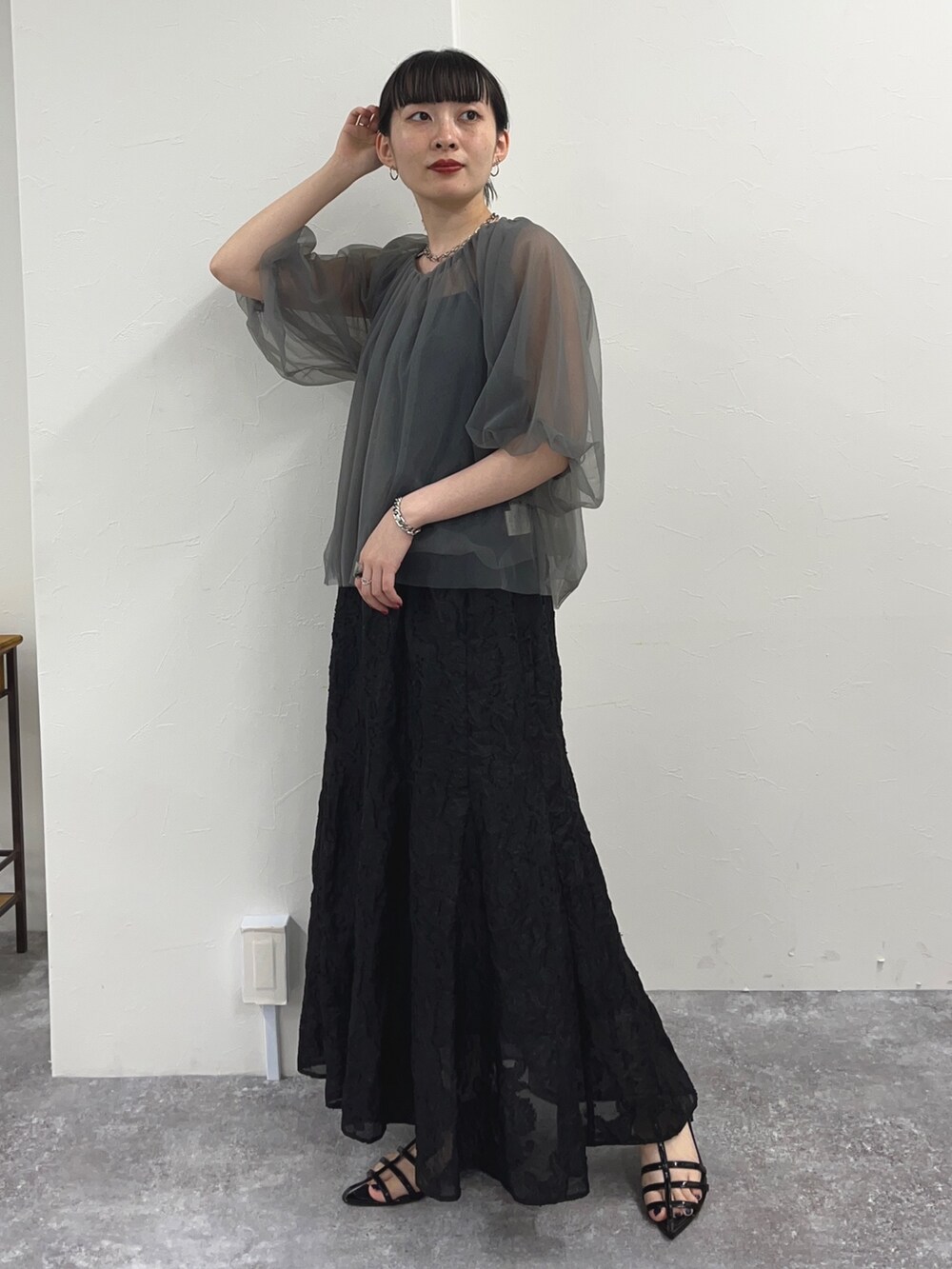 グレー系のシャツ/ブラウス、ブラック系のスカート、ブラック系のサンダルを着用したレディースの夏コーディネートの2枚目の写真