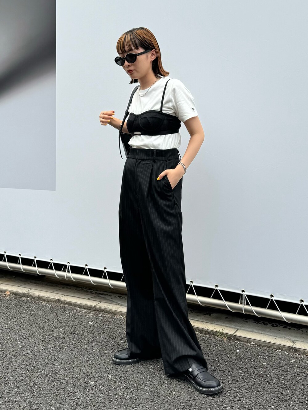 ホワイト系のTシャツ/カットソー、ブラック系のスラックス、ブラック系のハンドバッグを着用したレディースの夏コーディネートの2枚目の写真