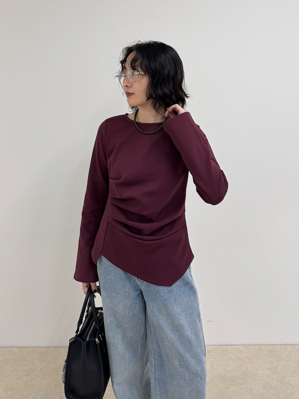 レッド系のTシャツ/カットソー、ブルー系のデニムパンツ、ブラック系のボストンバッグを着用したレディースの秋コーディネートの4枚目の写真