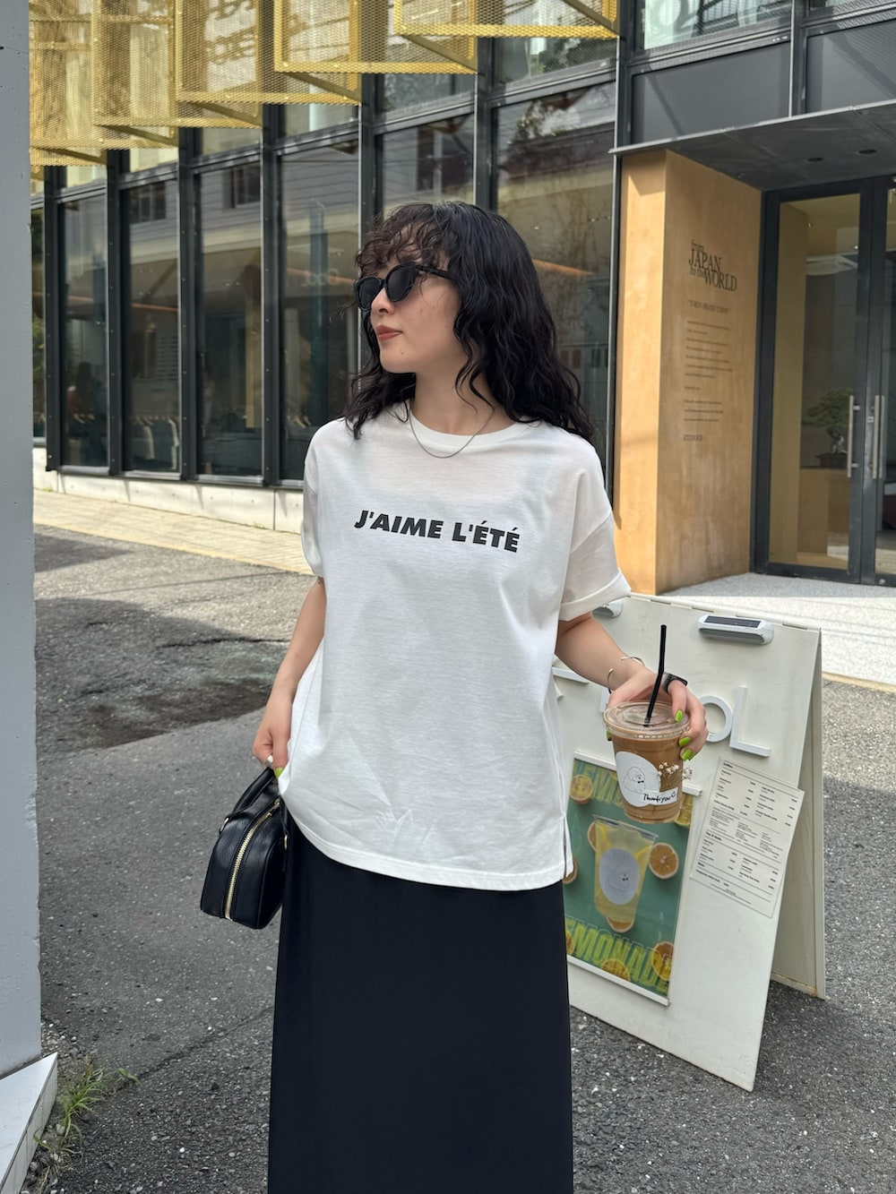 ホワイト系のTシャツ/カットソー、ブラック系のスカート、ブラック系のショルダーバッグを着用したレディースの夏コーディネートの7枚目の写真