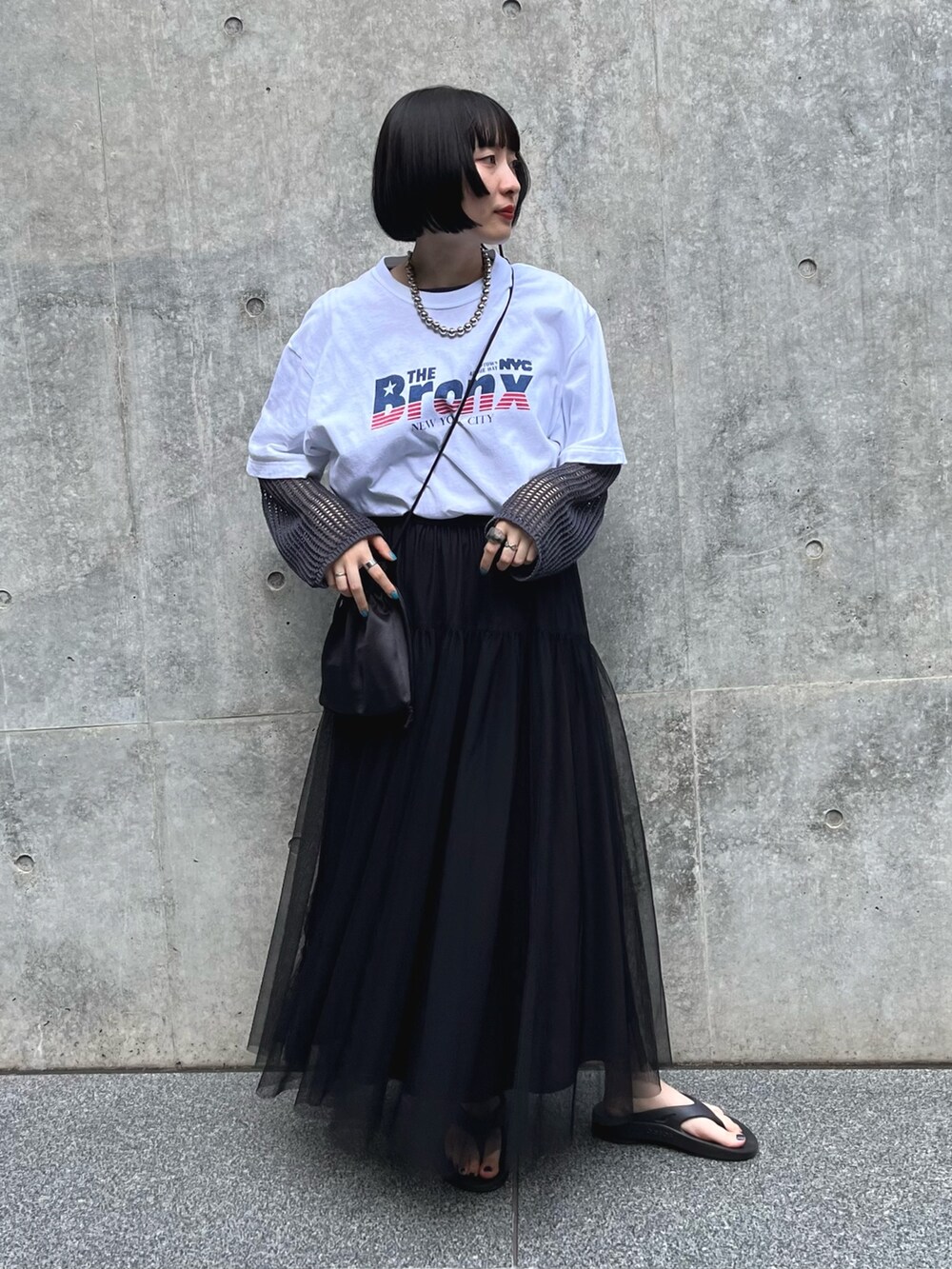 ホワイト系のTシャツ/カットソー、ブラック系のスカート、グレー系のニット/セーターを着用したレディースの夏コーディネートの2枚目の写真