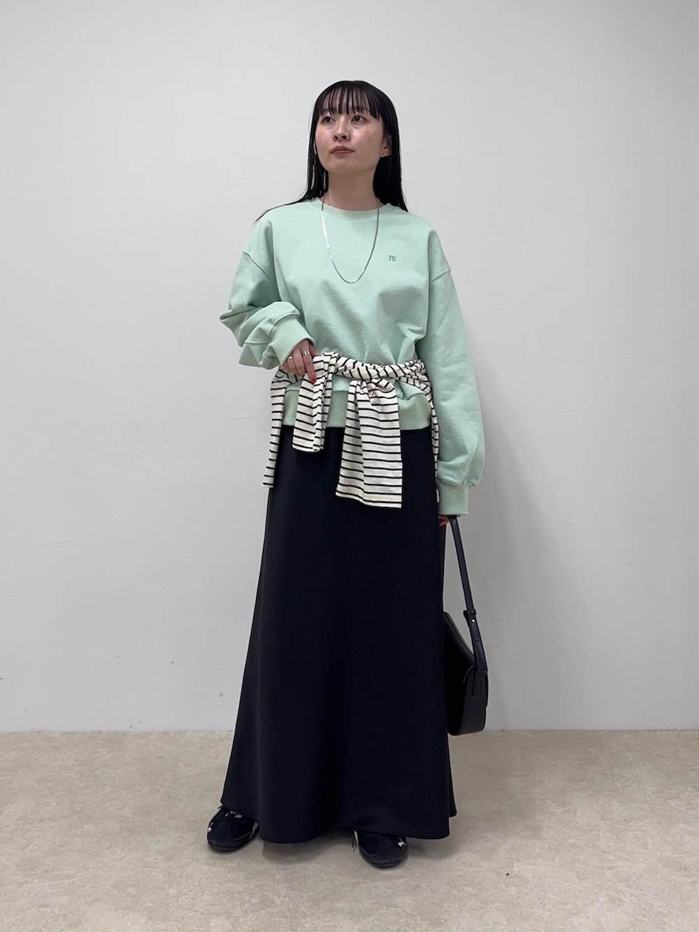 グリーン系のスウェット、ブラック系のスカート、ホワイト系のTシャツ/カットソーを着用したレディースの冬コーディネートの4枚目の写真