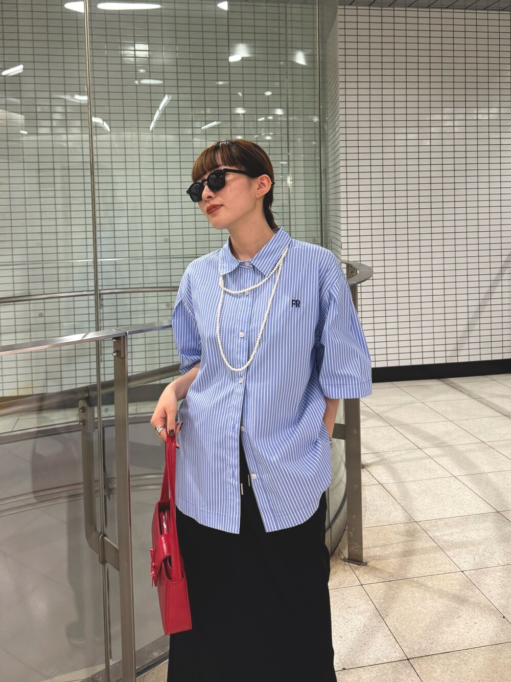 ブラック系のスカート、ブルー系のシャツ/ブラウス、ホワイト系のネックレスを着用したレディースの夏コーディネートの3枚目の写真