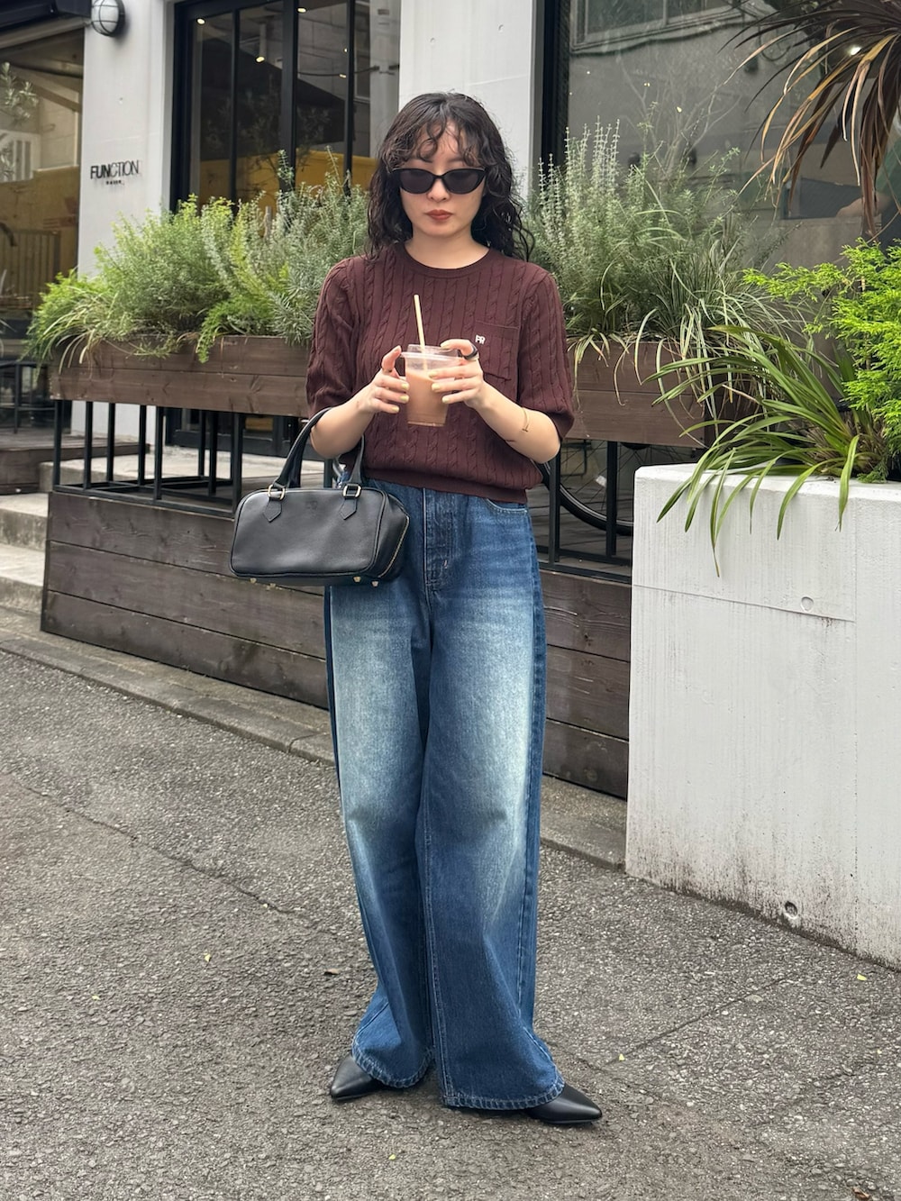 ブラウン系のニット/セーター、ブルー系のデニムパンツ、ブラック系のショルダーバッグを着用したレディースの夏コーディネートの5枚目の写真