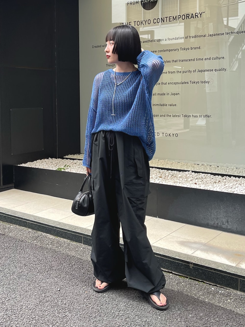 ブルー系のニット/セーター、ブラック系のカーゴパンツ、ブラック系のサンダルを着用したレディースの夏コーディネートの2枚目の写真