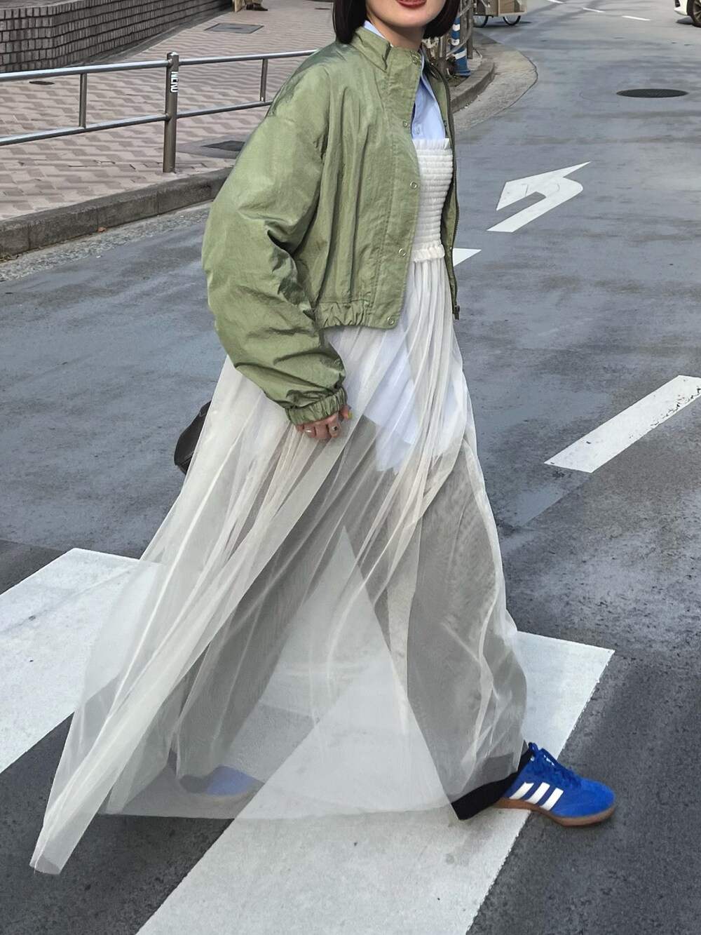 グリーン系のブルゾン、ホワイト系のワンピース、ブラック系のその他パンツを着用したレディースの冬コーディネートの3枚目の写真