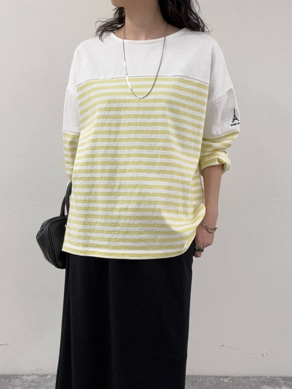 イエロー系のTシャツ/カットソー、ブラック系のスカート、ブラック系のショルダーバッグを着用したレディースの春コーディネートの6枚目の写真