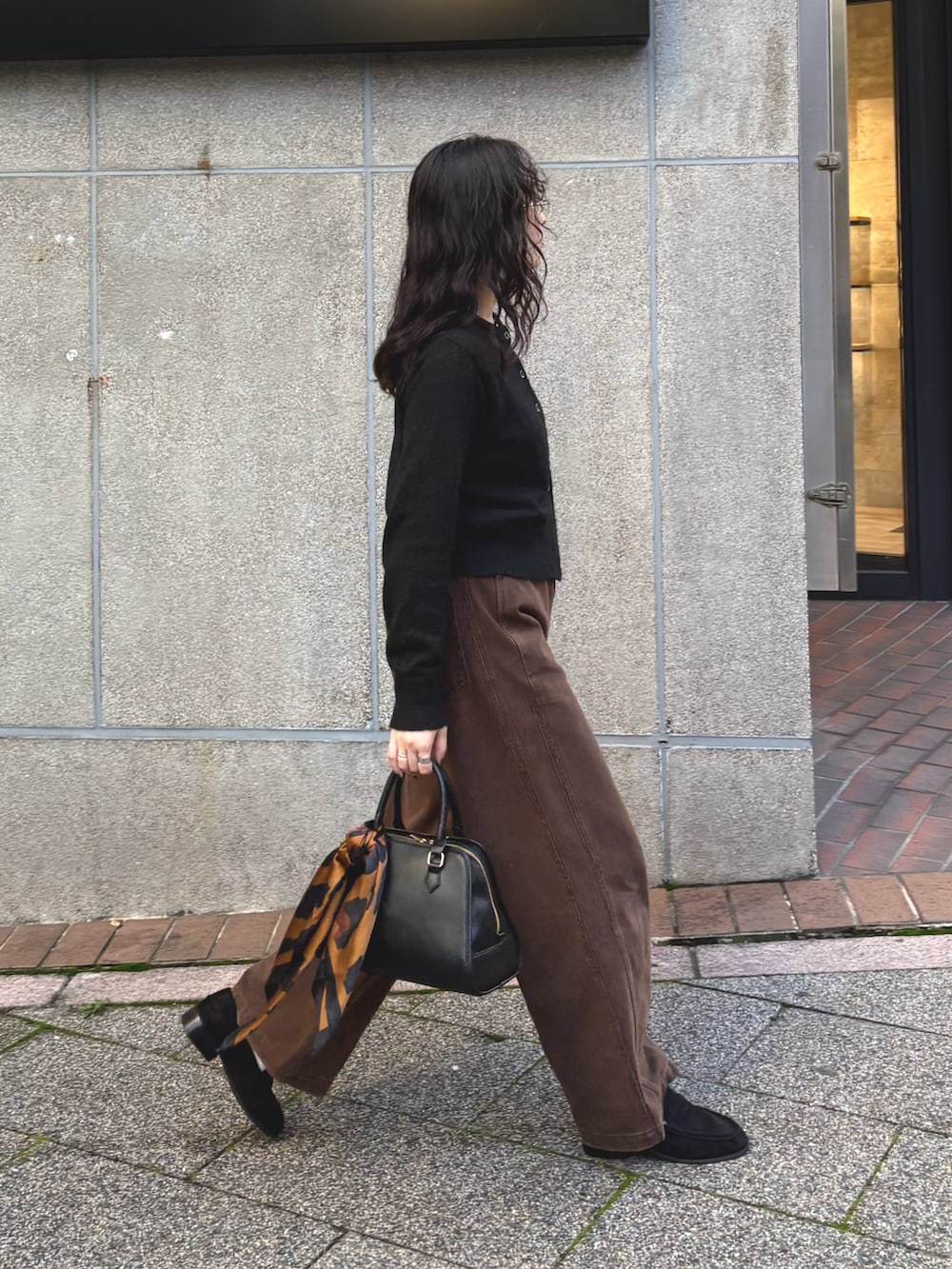 ブラック系のカーディガン/ボレロ、ブラウン系のその他パンツ、ブラック系のショルダーバッグを着用したレディースの秋コーディネートの2枚目の写真