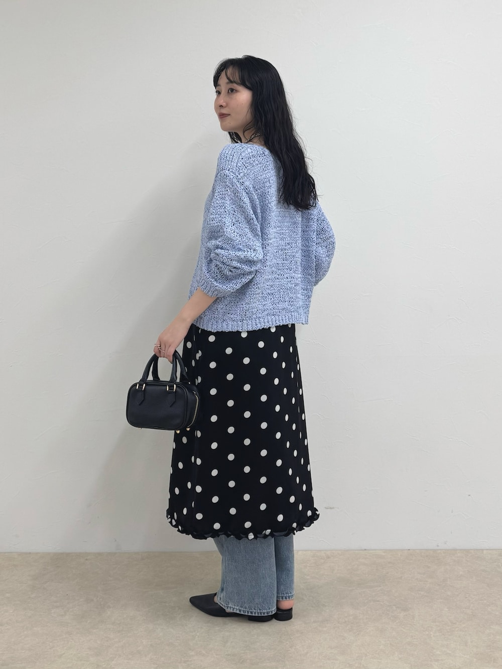 ブルー系のニット/セーター、ブラック系のスカート、ブルー系のデニムパンツを着用したレディースの春コーディネートの3枚目の写真