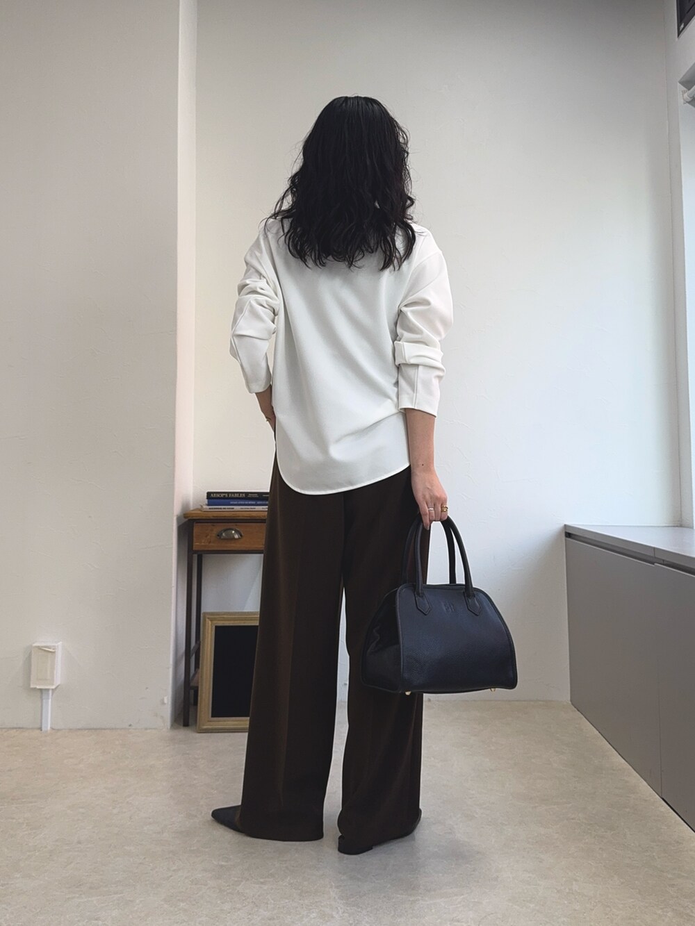 ホワイト系のTシャツ/カットソー、ブラック系のショルダーバッグ、ブラウン系のスラックスを着用したレディースの夏コーディネートの6枚目の写真