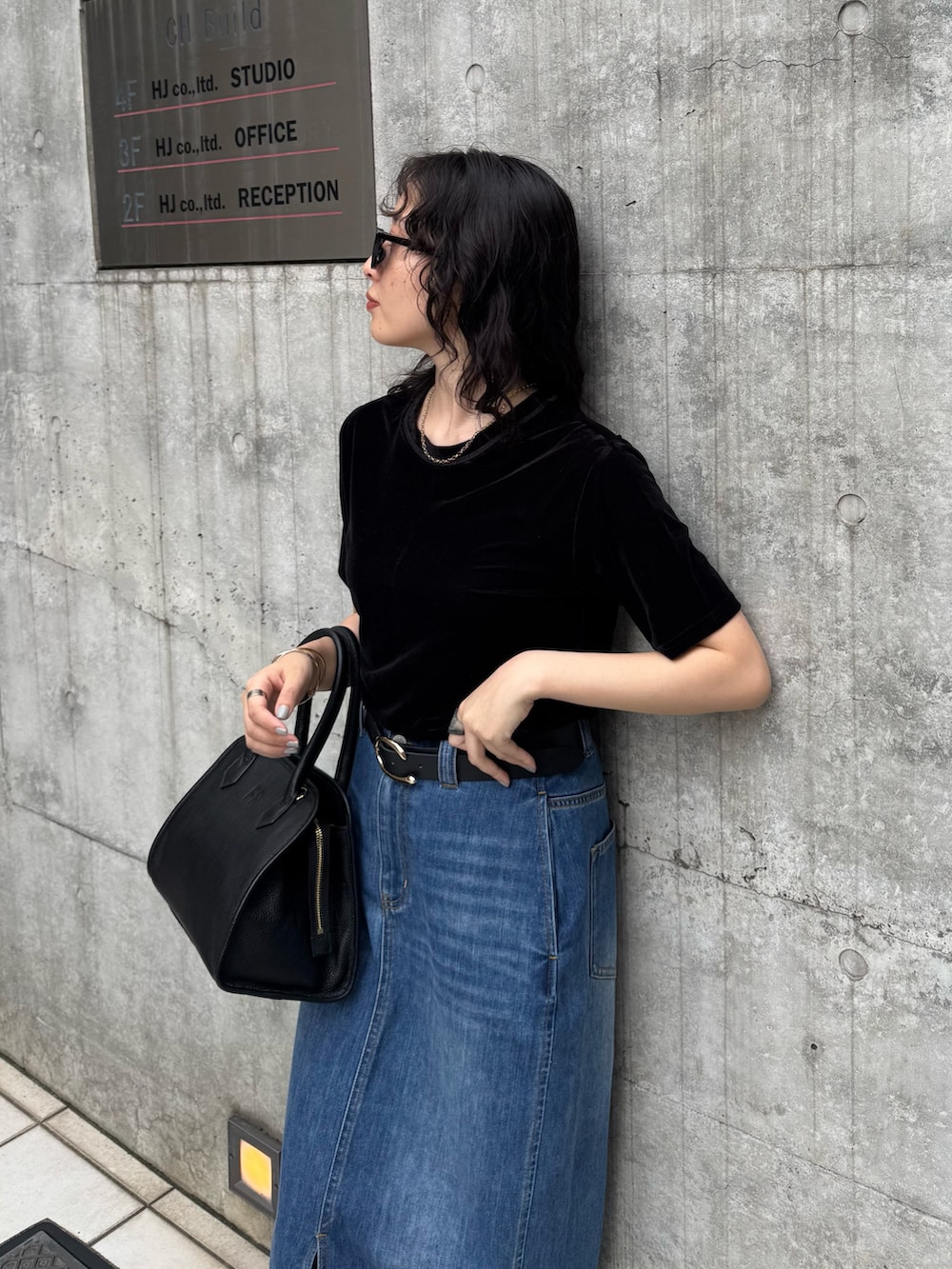 ブラック系のTシャツ/カットソー、ブルー系のデニムスカート、ブラック系のショルダーバッグを着用したレディースの夏コーディネートの3枚目の写真