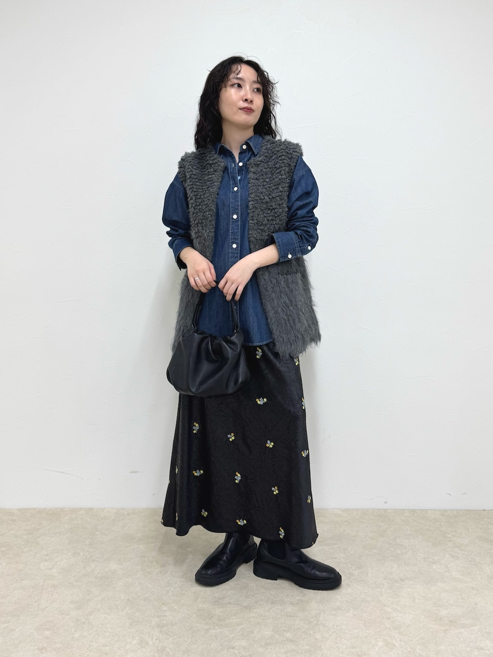 ブルー系のシャツ/ブラウス、グレー系のベスト、ブラック系のスカートを着用したレディースの秋コーディネートの2枚目の写真