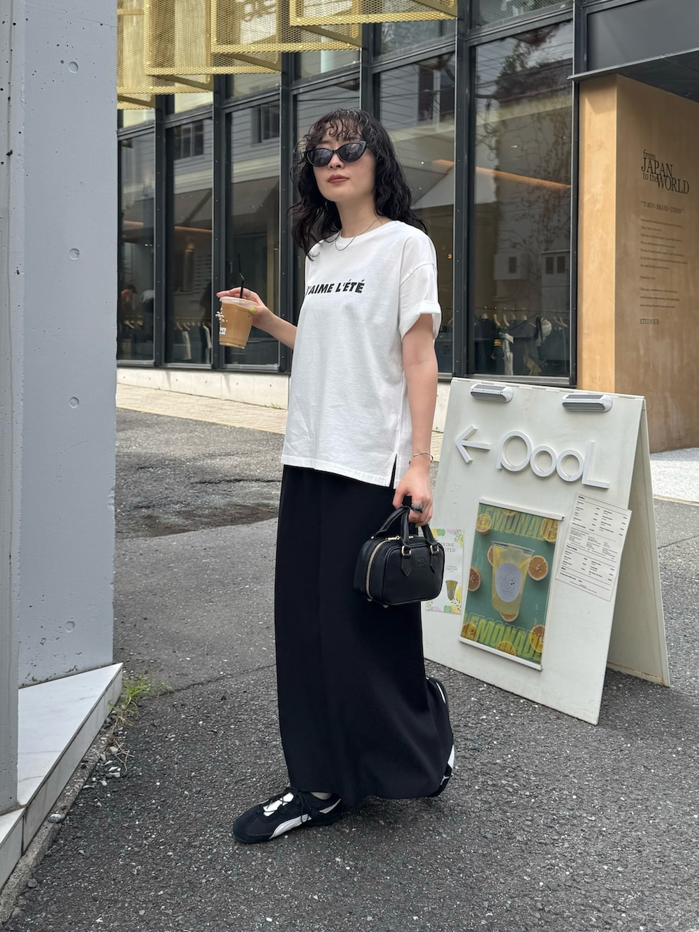 ホワイト系のTシャツ/カットソー、ブラック系のスカート、ブラック系のショルダーバッグを着用したレディースの夏コーディネートの3枚目の写真