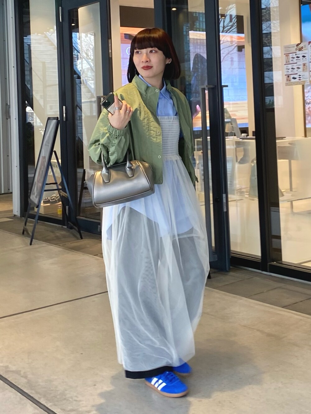 グリーン系のブルゾン、ホワイト系のワンピース、ブラック系のその他パンツを着用したレディースの冬コーディネートの2枚目の写真