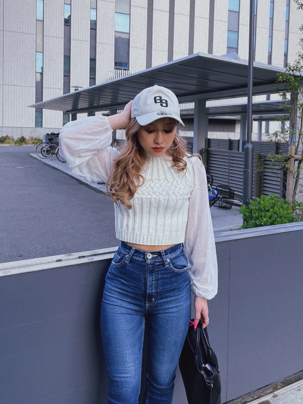 ホワイト系のニット/セーター、ブラック系のハンドバッグ、ベージュ系のキャップを着用したレディースの春コーディネートの3枚目の写真