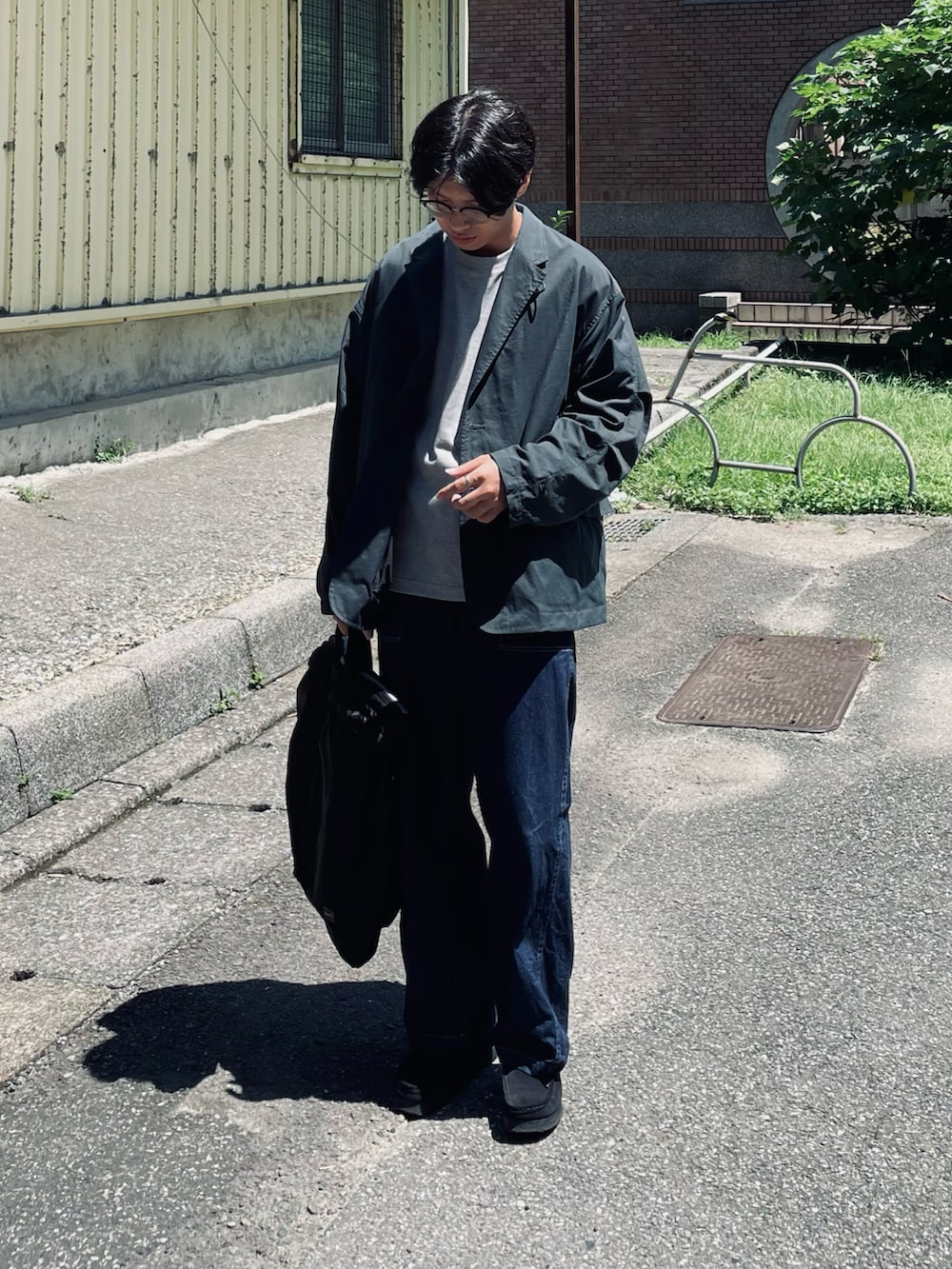 グレー系のTシャツ/カットソー、ブラック系のその他アウター、ブルー系のデニムパンツを着用したメンズの秋コーディネートの3枚目の写真