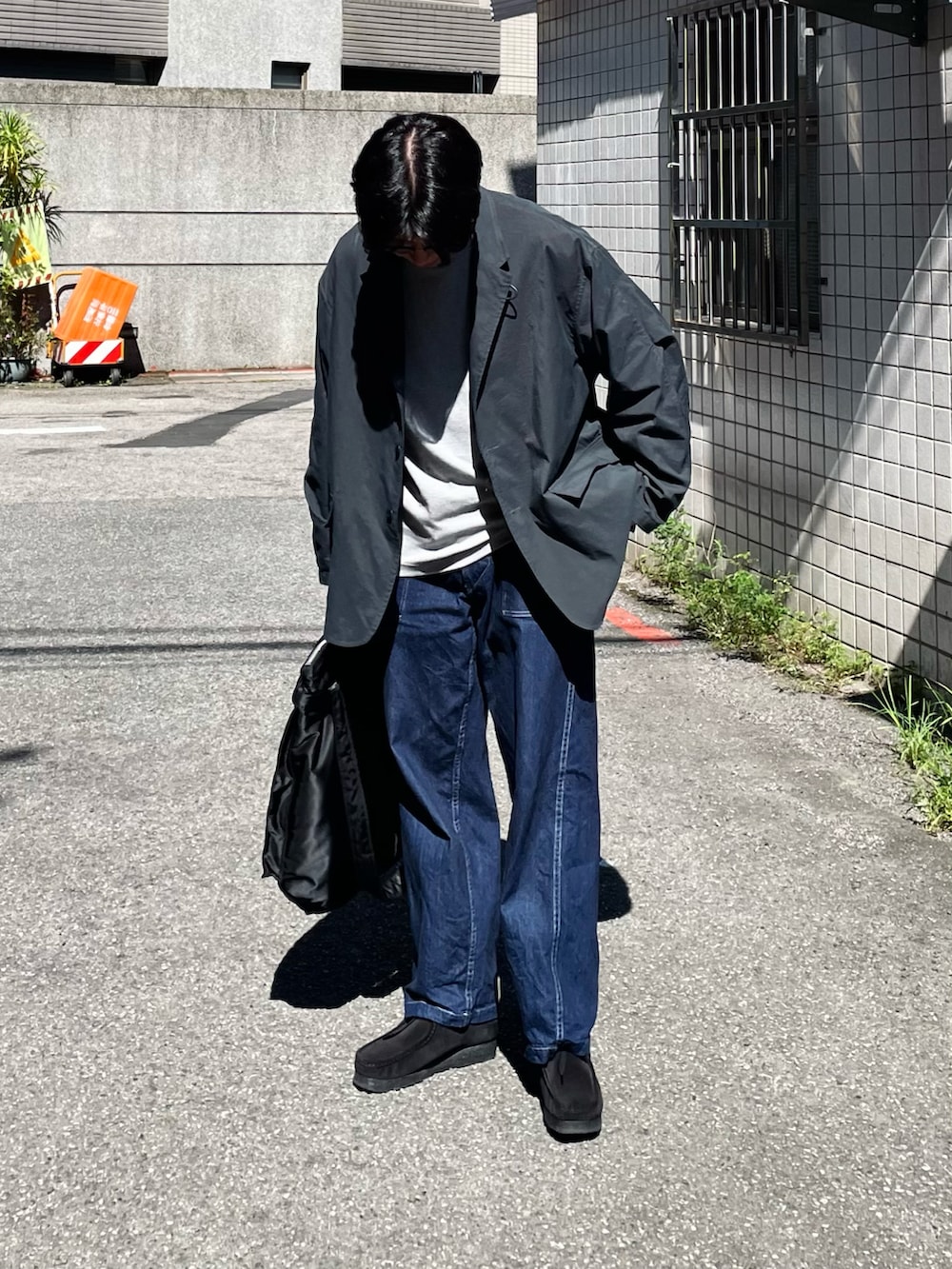 グレー系のTシャツ/カットソー、ブラック系のその他アウター、ブルー系のデニムパンツを着用したメンズの秋コーディネートの4枚目の写真