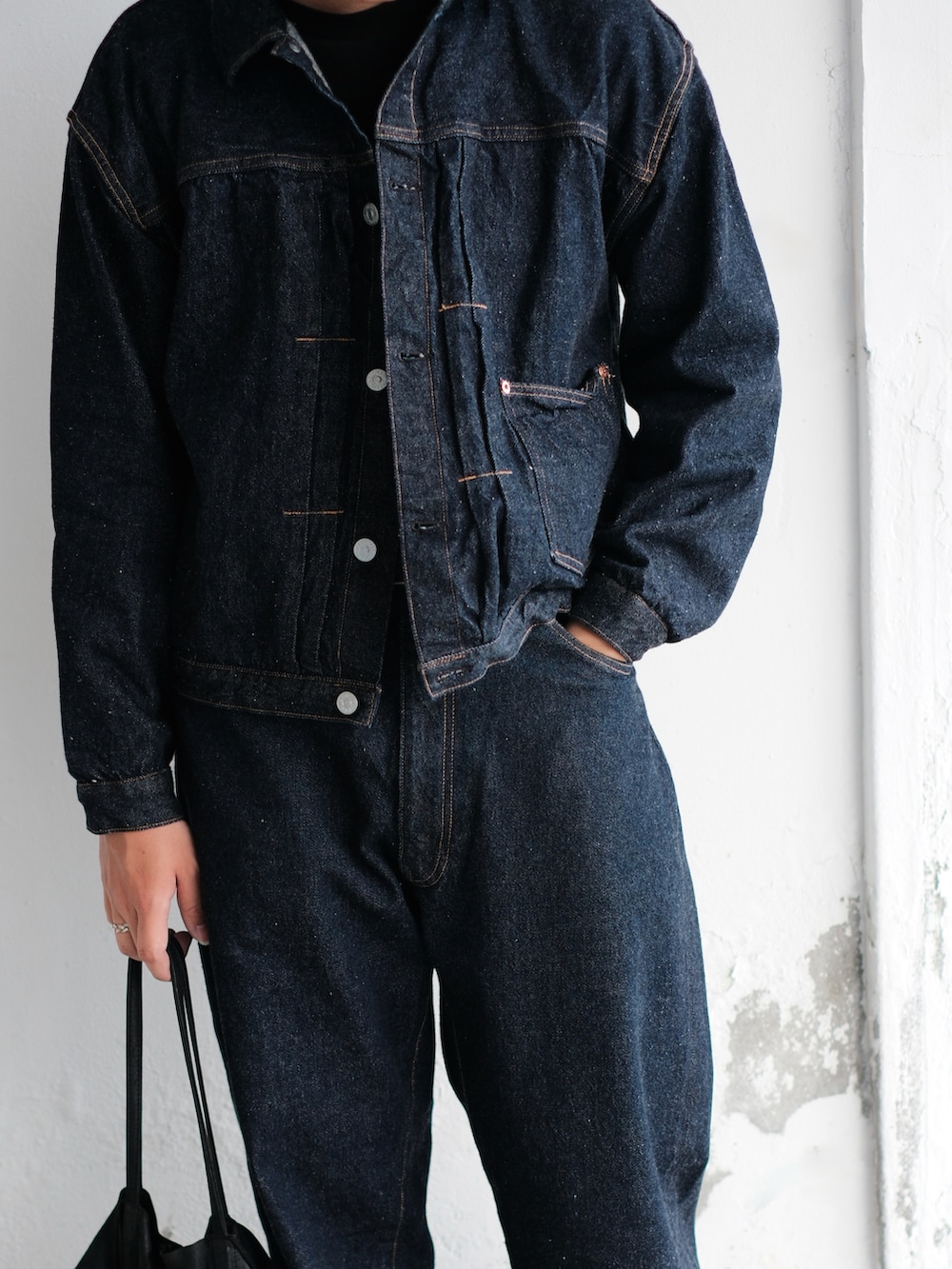 ブルー系のデニムパンツ、ブラック系のブーツ、ブラック系のトートバッグを着用したメンズの冬コーディネートの2枚目の写真