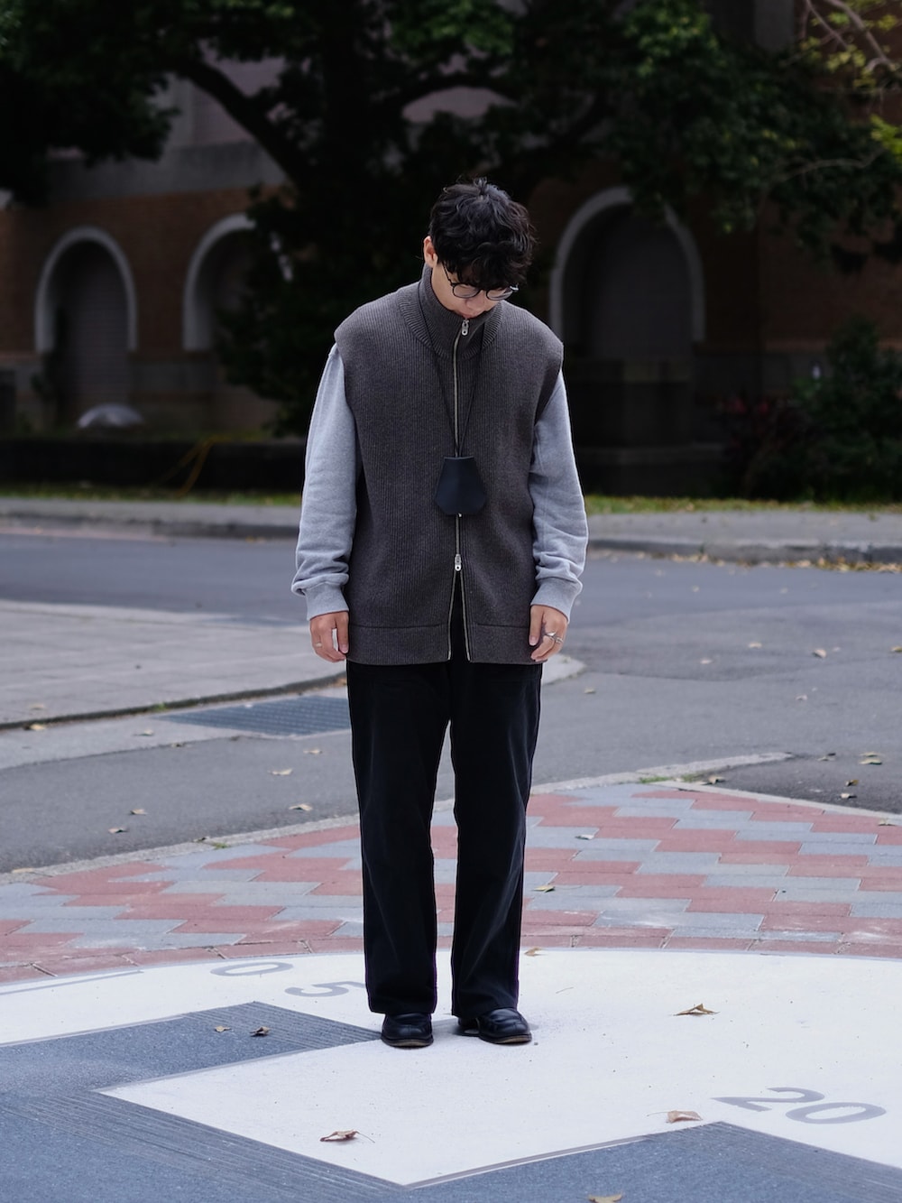 グレー系のベスト、グレー系のトップス、ブラック系のパンツを着用したメンズの春コーディネートの3枚目の写真