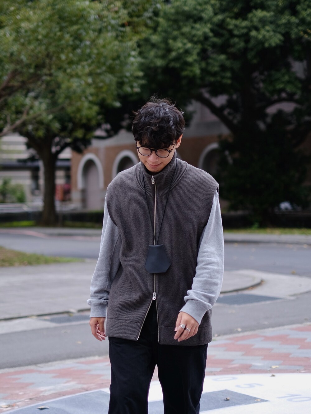 グレー系のベスト、グレー系のトップス、ブラック系のパンツを着用したメンズの春コーディネートの5枚目の写真