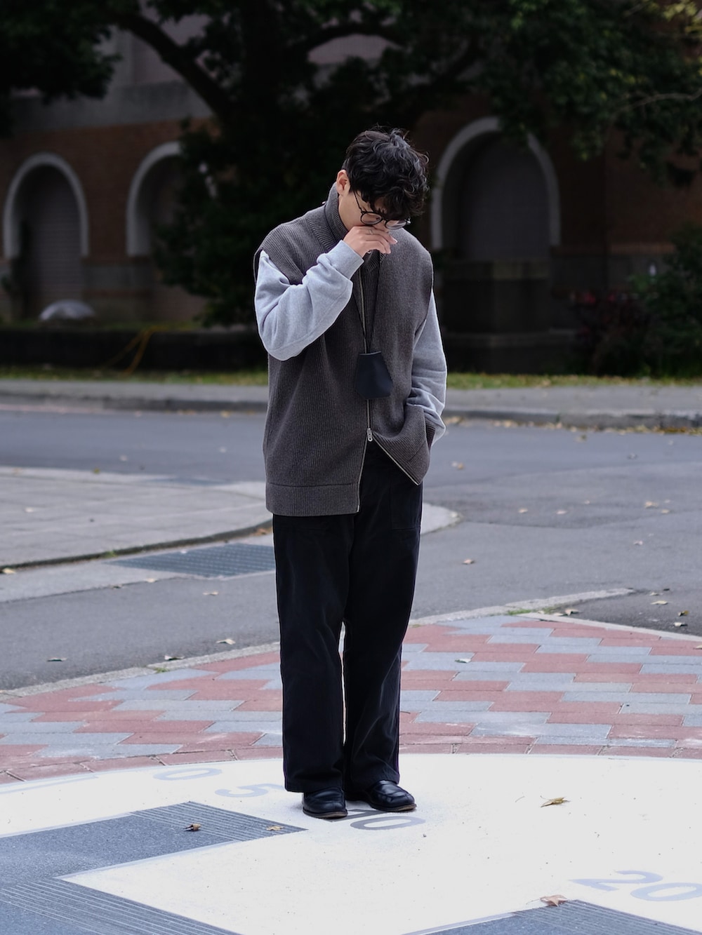 グレー系のベスト、グレー系のトップス、ブラック系のパンツを着用したメンズの春コーディネートの4枚目の写真