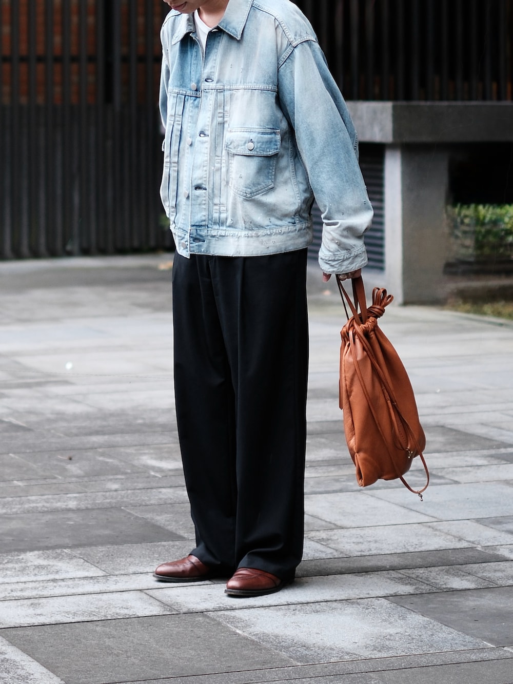 ブラック系のスラックス、ブラウン系のバッグ、ブラウン系のローファーを着用したメンズの冬コーディネートの2枚目の写真