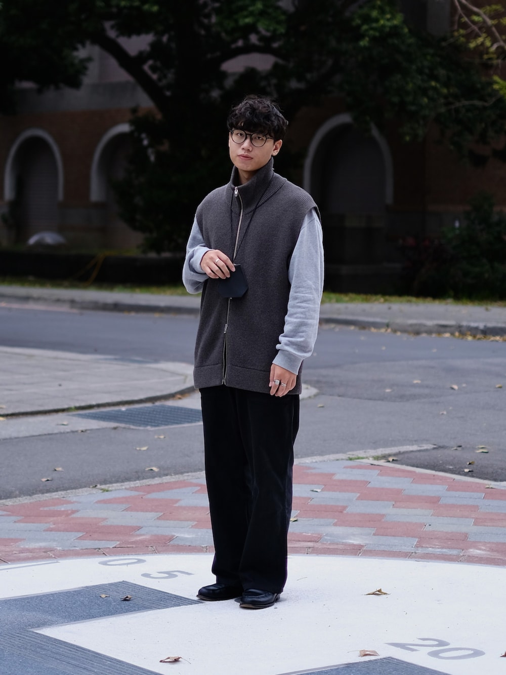 グレー系のベスト、グレー系のトップス、ブラック系のパンツを着用したメンズの春コーディネートの2枚目の写真