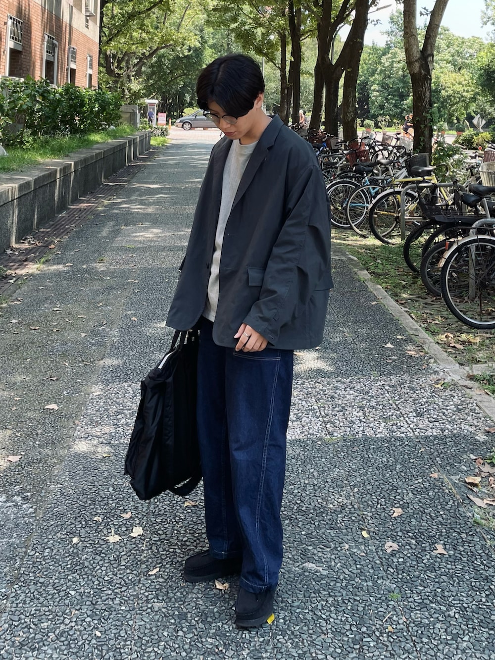 グレー系のTシャツ/カットソー、ブラック系のその他アウター、ブルー系のデニムパンツを着用したメンズの秋コーディネートの2枚目の写真