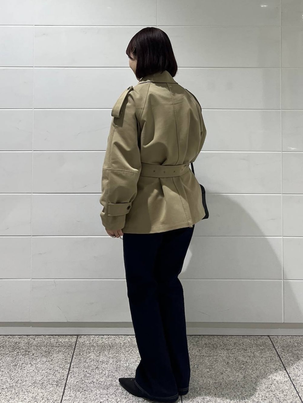 ブラック系のハンドバッグ、ブルー系のデニムパンツ、ブラック系のパンプスを着用したレディースの冬コーディネートの3枚目の写真