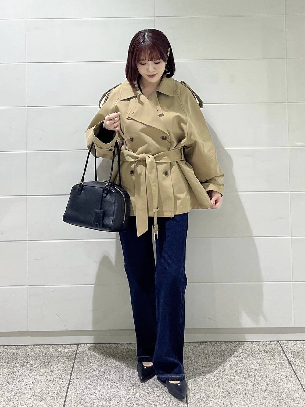 ブラック系のハンドバッグ、ブルー系のデニムパンツ、ブラック系のパンプスを着用したレディースの冬コーディネートの2枚目の写真