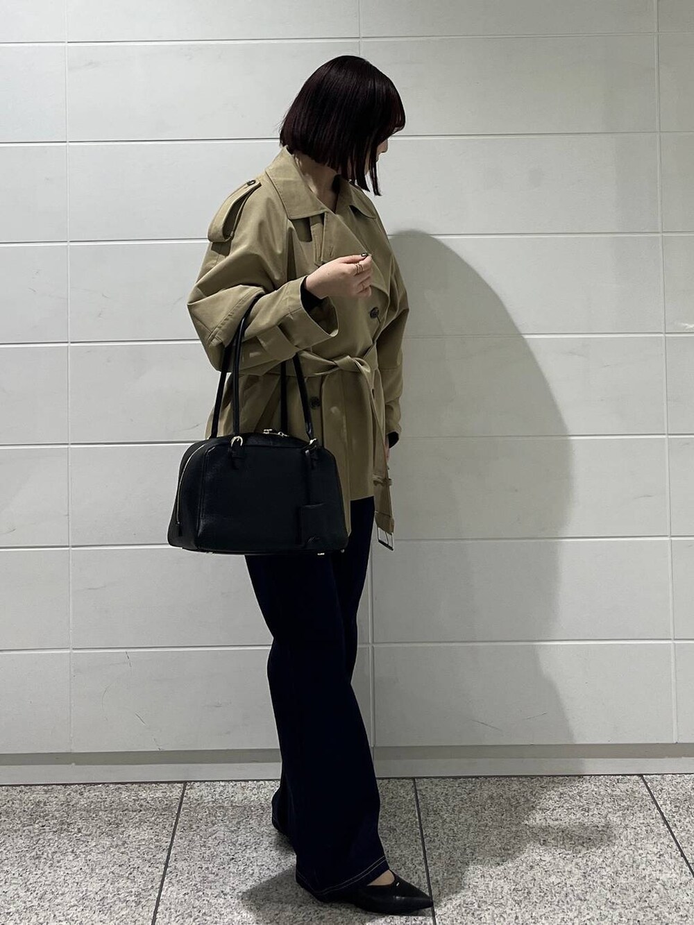 ブラック系のハンドバッグ、ブルー系のデニムパンツ、ブラック系のパンプスを着用したレディースの冬コーディネートの6枚目の写真