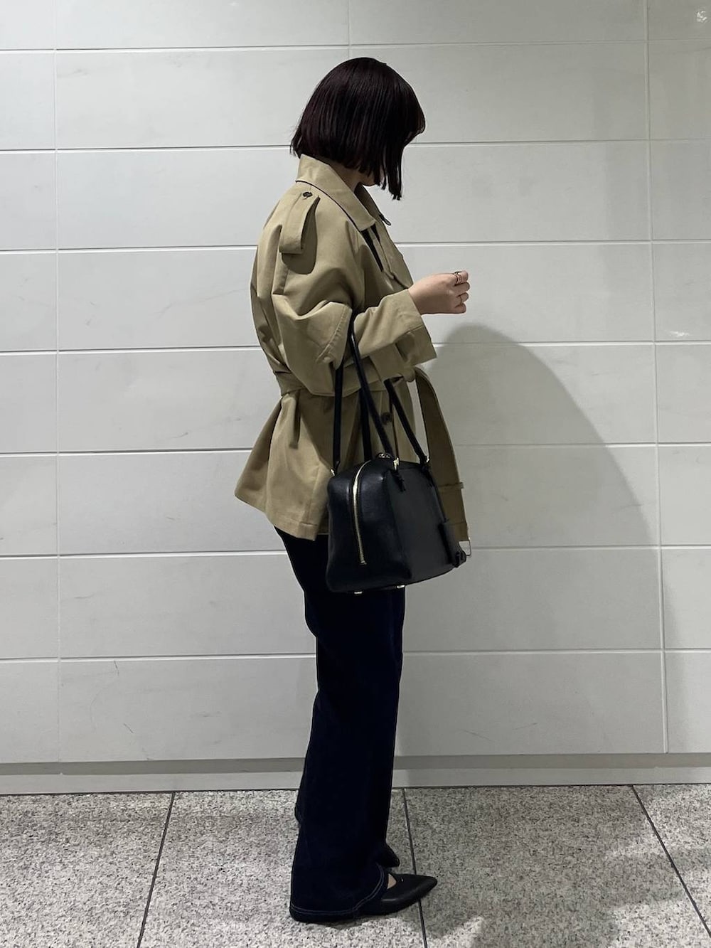 ブラック系のハンドバッグ、ブルー系のデニムパンツ、ブラック系のパンプスを着用したレディースの冬コーディネートの5枚目の写真