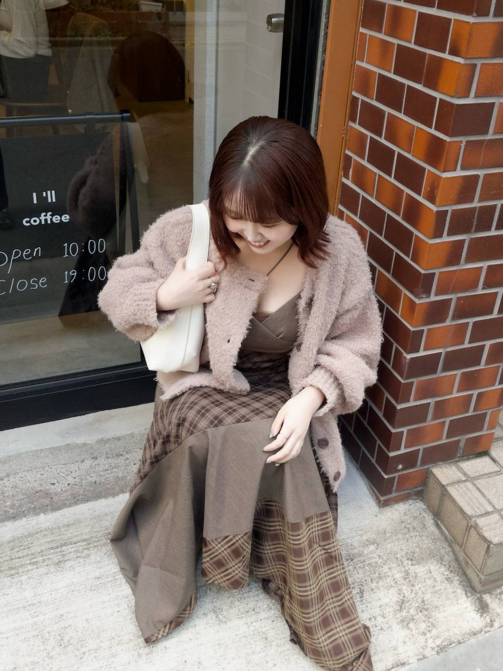 ホワイト系のショルダーバッグ、ベージュ系のカーディガン/ボレロ、ブラウン系のワンピースを着用したレディースの秋コーディネートの2枚目の写真