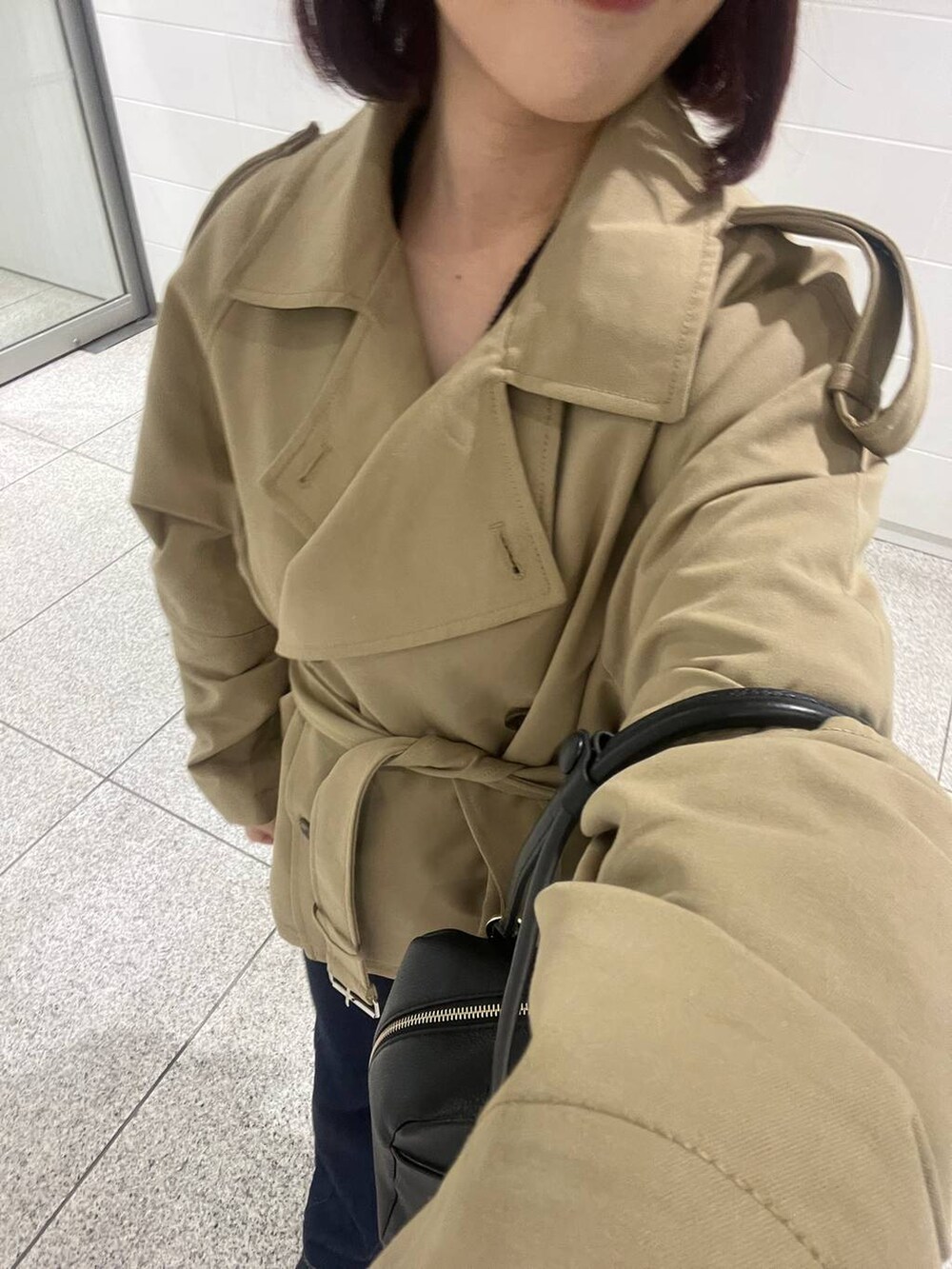 ブラック系のハンドバッグ、ブルー系のデニムパンツ、ブラック系のパンプスを着用したレディースの冬コーディネートの7枚目の写真