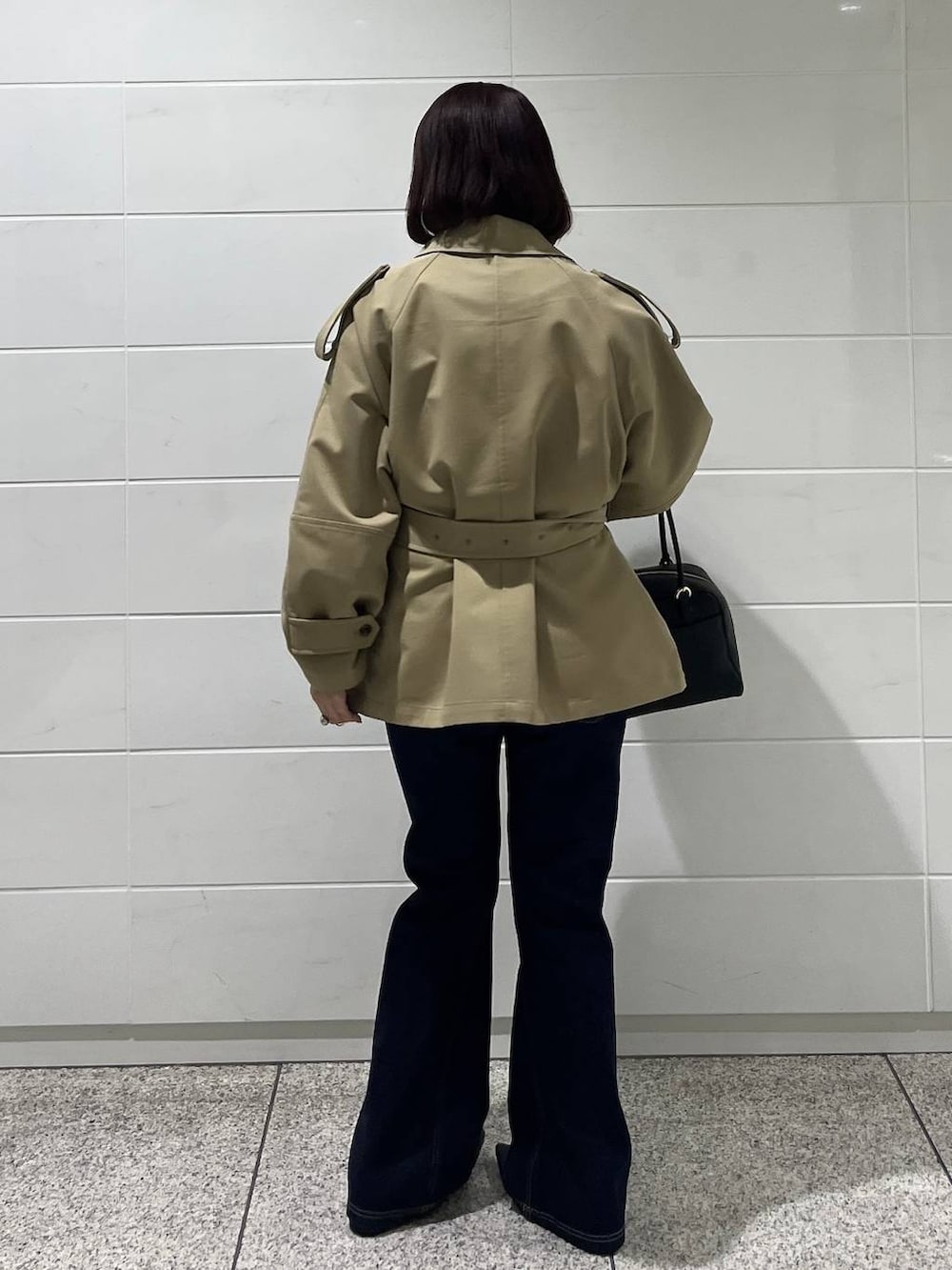 ブラック系のハンドバッグ、ブルー系のデニムパンツ、ブラック系のパンプスを着用したレディースの冬コーディネートの4枚目の写真