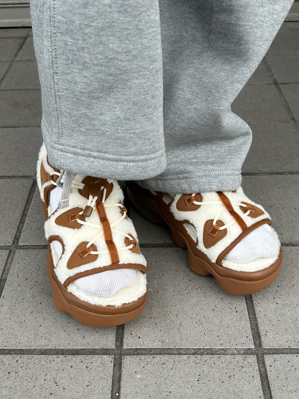 ホワイト系のTシャツ/カットソー、ブラウン系のサンダル、グレー系のスウェットパンツを着用したレディースの秋コーディネートの5枚目の写真