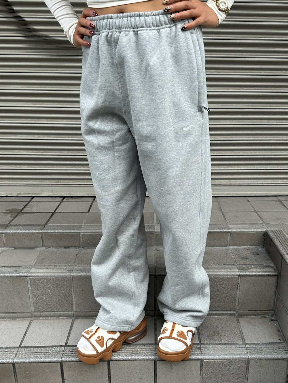 ホワイト系のTシャツ/カットソー、ブラウン系のサンダル、グレー系のスウェットパンツを着用したレディースの秋コーディネートの3枚目の写真