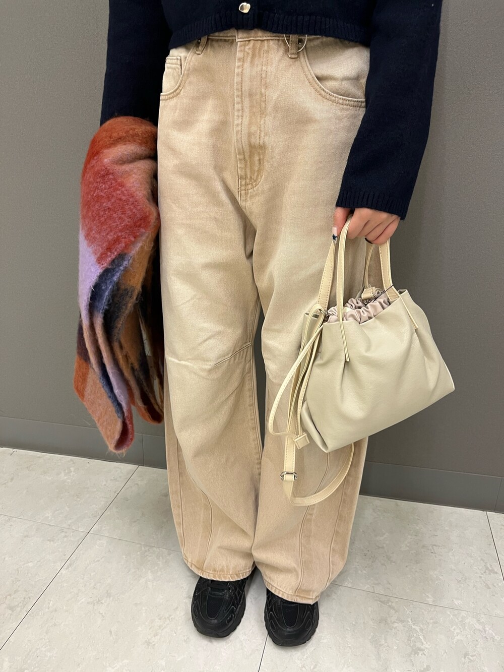 ブルー系のカーディガン/ボレロ、ベージュ系のデニムパンツ、ホワイト系のショルダーバッグを着用したレディースの冬コーディネートの3枚目の写真