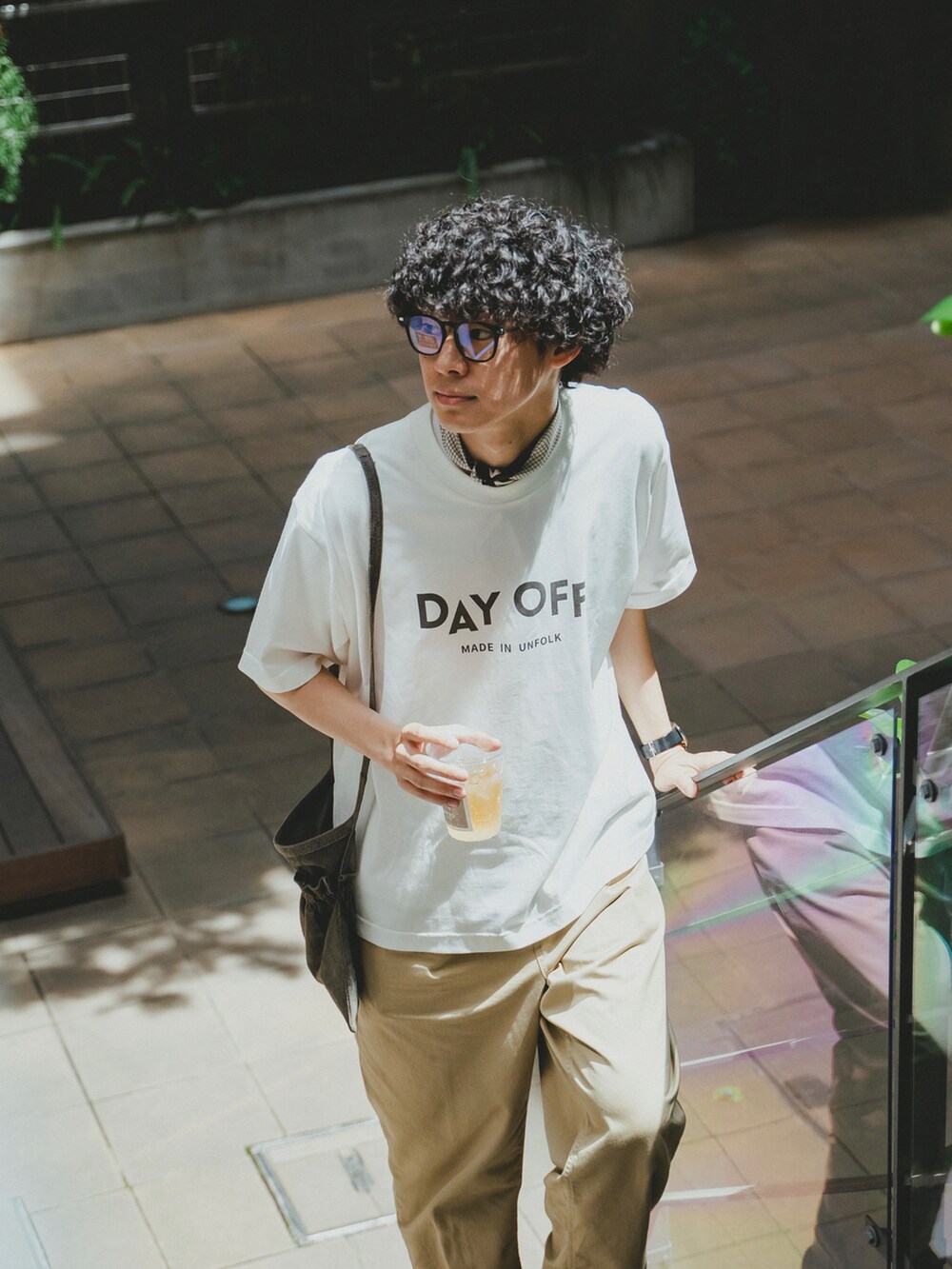 ホワイト系のTシャツ/カットソー、ベージュ系のチノパンツ、ブラック系のブーツを着用したメンズの夏コーディネートの2枚目の写真