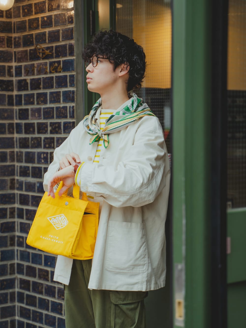 ホワイト系のカバーオール、イエロー系のTシャツ/カットソー、グリーン系のカーゴパンツを着用したメンズの春コーディネートの2枚目の写真