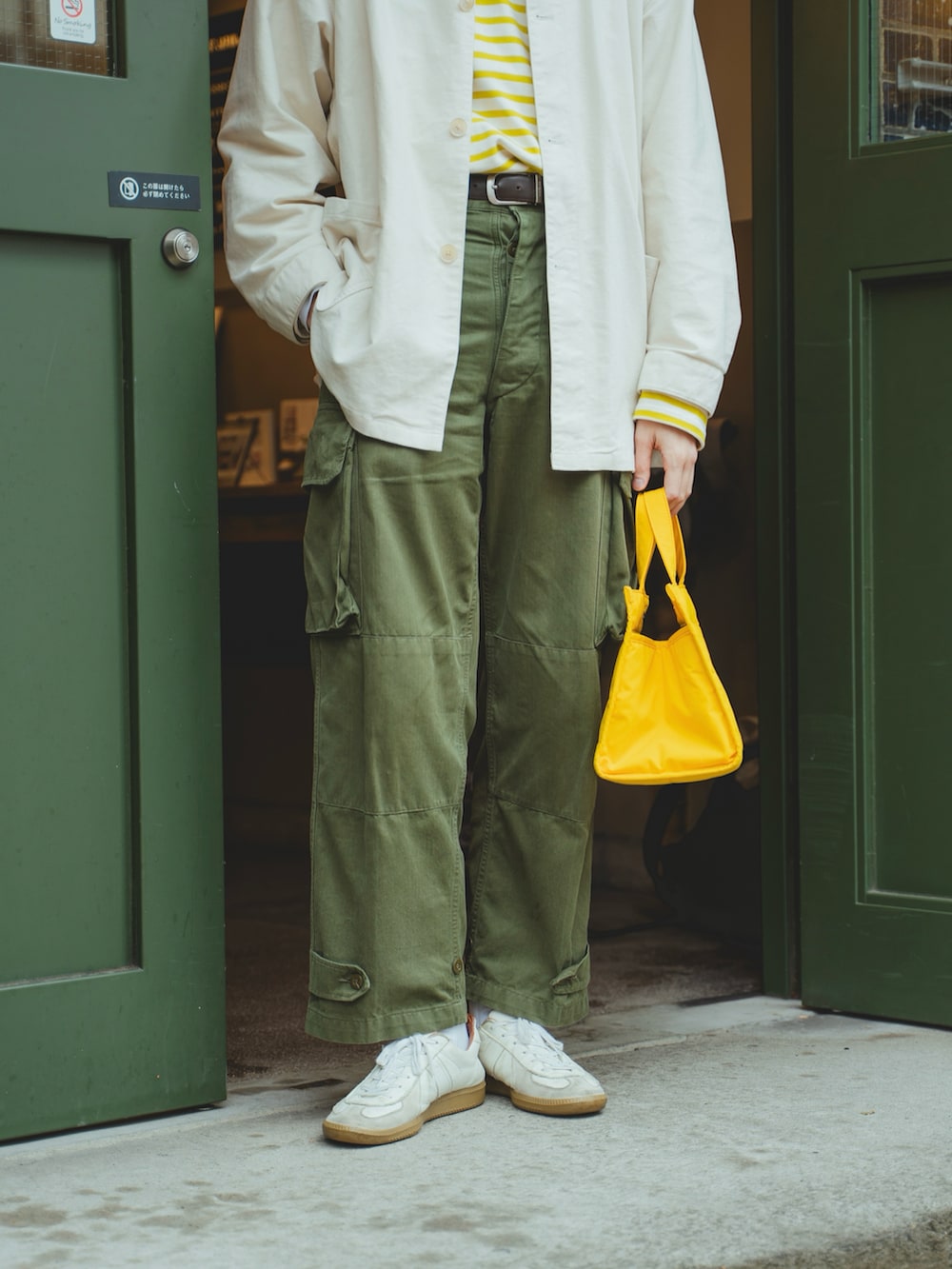 ホワイト系のカバーオール、イエロー系のTシャツ/カットソー、グリーン系のカーゴパンツを着用したメンズの春コーディネートの4枚目の写真