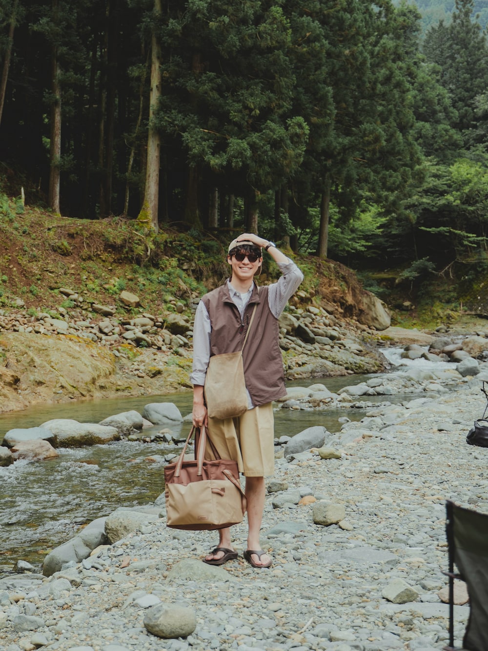 ブラウン系のベスト、ベージュ系のショルダーバッグ、ブラウン系のサンダルを着用したメンズの夏コーディネートの3枚目の写真